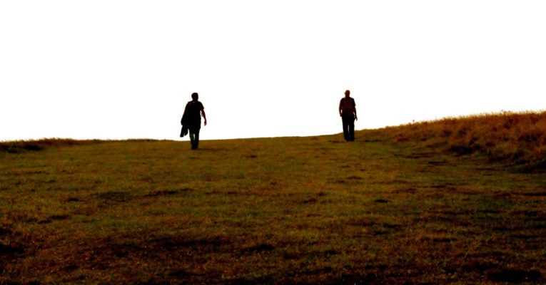 two guys walking in field